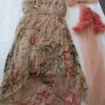 1920s pink beaded net evening dress laid flat with sash and feather trim accessories, after conservation treatment.