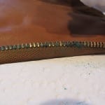 Heavily corroded brass zipper teeth on a leather flight suit.