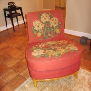 Restored needlework slipper chair with floral seat and back, on parquet floor.