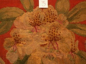 Post-conservation detail labeled "3" showing the previously damaged area of a floral needlework chair seat now in-filled with re-woven tan, gold, and brown wool stitching.
