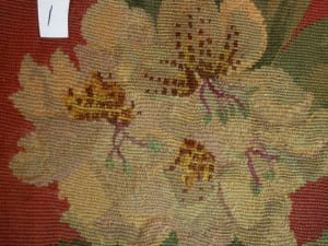 Post-conservation detail labeled "1" showing the previously heavily damaged needlework area now stabilized, with gold, tan, and rust floral motifs re-woven into the repaired zone.