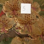 Needlework chair seat area 3 before conservation, showing major loss and exposed backing.
