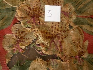 Needlework chair seat area 3 before conservation, showing major loss and exposed backing.