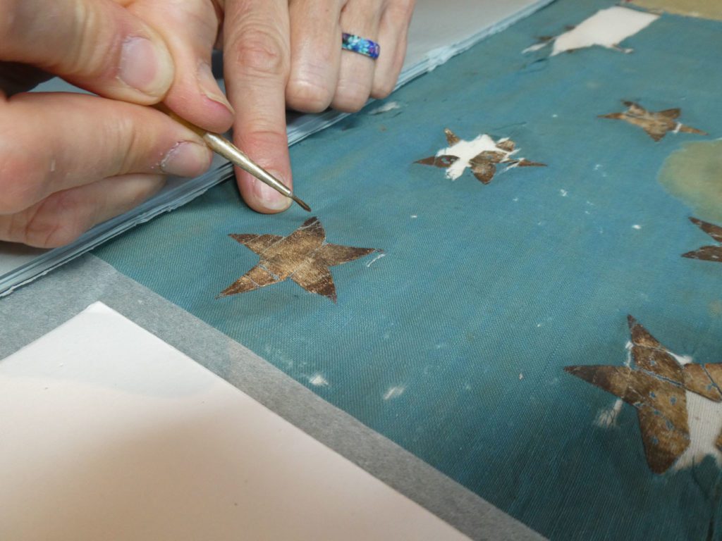 close up of painted fabric star being repaired by hand