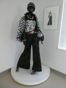 Mannequin displaying a black-and-white fashion ensemble with patterned jacket, wide-leg pants, and accessories, designed by Franca Bartoli, Italian American Museum.