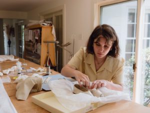 Annabel Dobbyn carefully places white tissues inside Mother Seton's ivory silk slippers during treatment process.